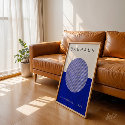 bauhaus style decorative art with light wood frame displayed leaning on a brown leather sofa in a well-lit room