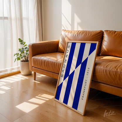 framed geometric wall art in blue and white bauhaus style leaning against brown sofa, light frame