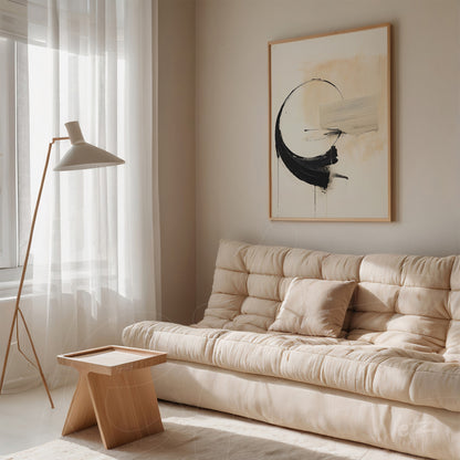 framed abstract artwork in light tones with black strokes displayed in a beige sofa setting featuring a modern lamp