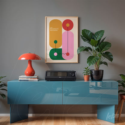 framed poster with colorful geometric art on gray wall above blue sideboard with plants and table lamp