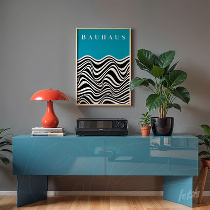 framed abstract black and white art with 'bauhaus' text, resting on a blue sideboard next to a red lamp and plants