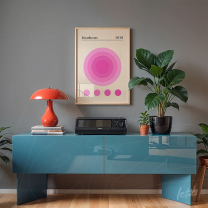 composition featuring a poster print of concentric pink circles framed, displayed on a gray wall with modernist decor