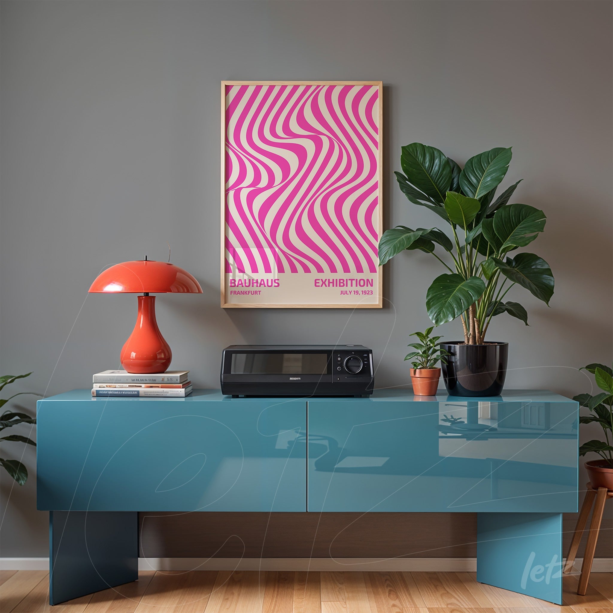 poster print with pink and white wavy pattern in a thin gold frame, displayed above a blue sideboard next to a green plant