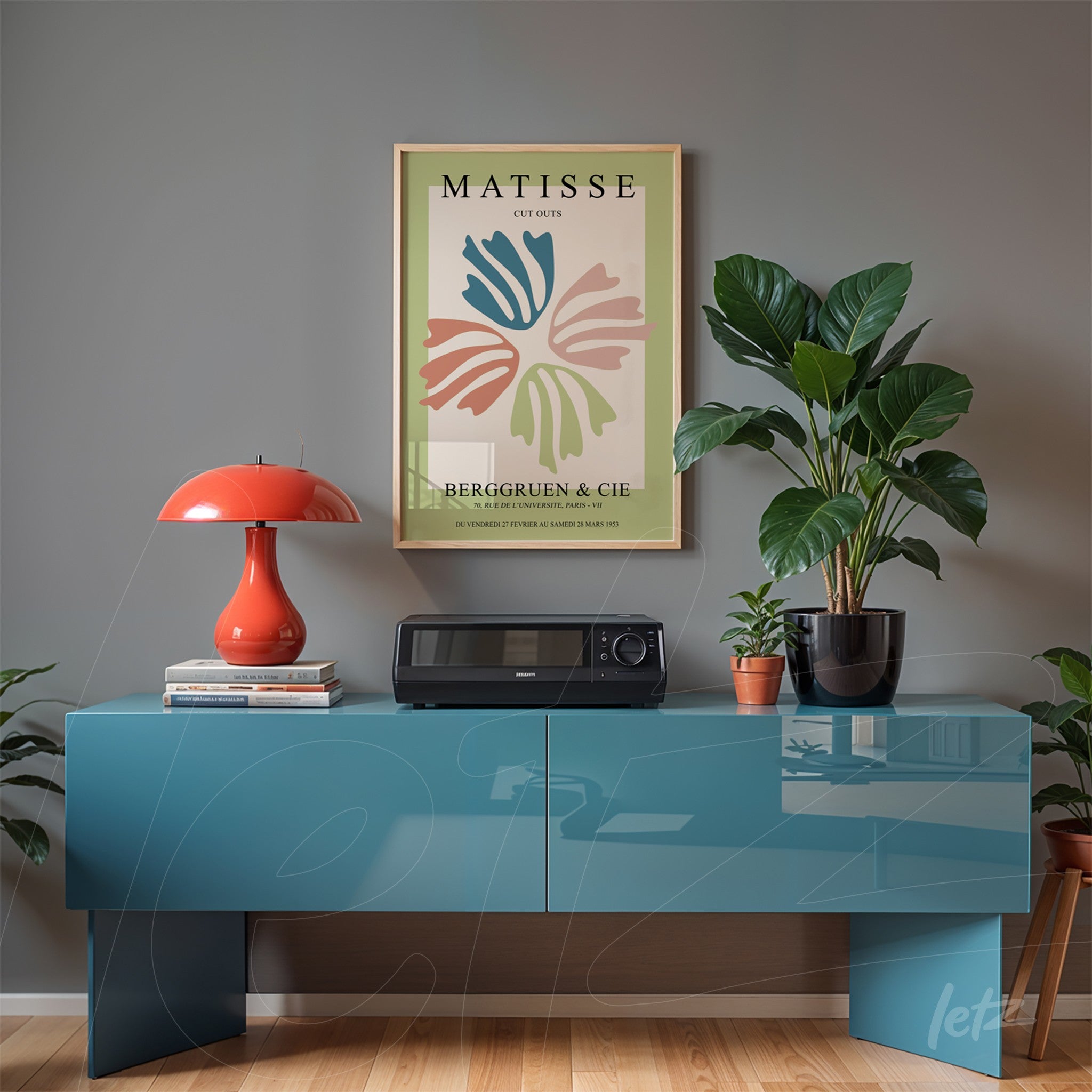 modern art print of leaves in soft colors in a golden frame displayed above a blue cabinet against a gray wall