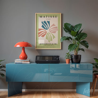 modern art print of leaves in soft colors in a golden frame displayed above a blue cabinet against a gray wall