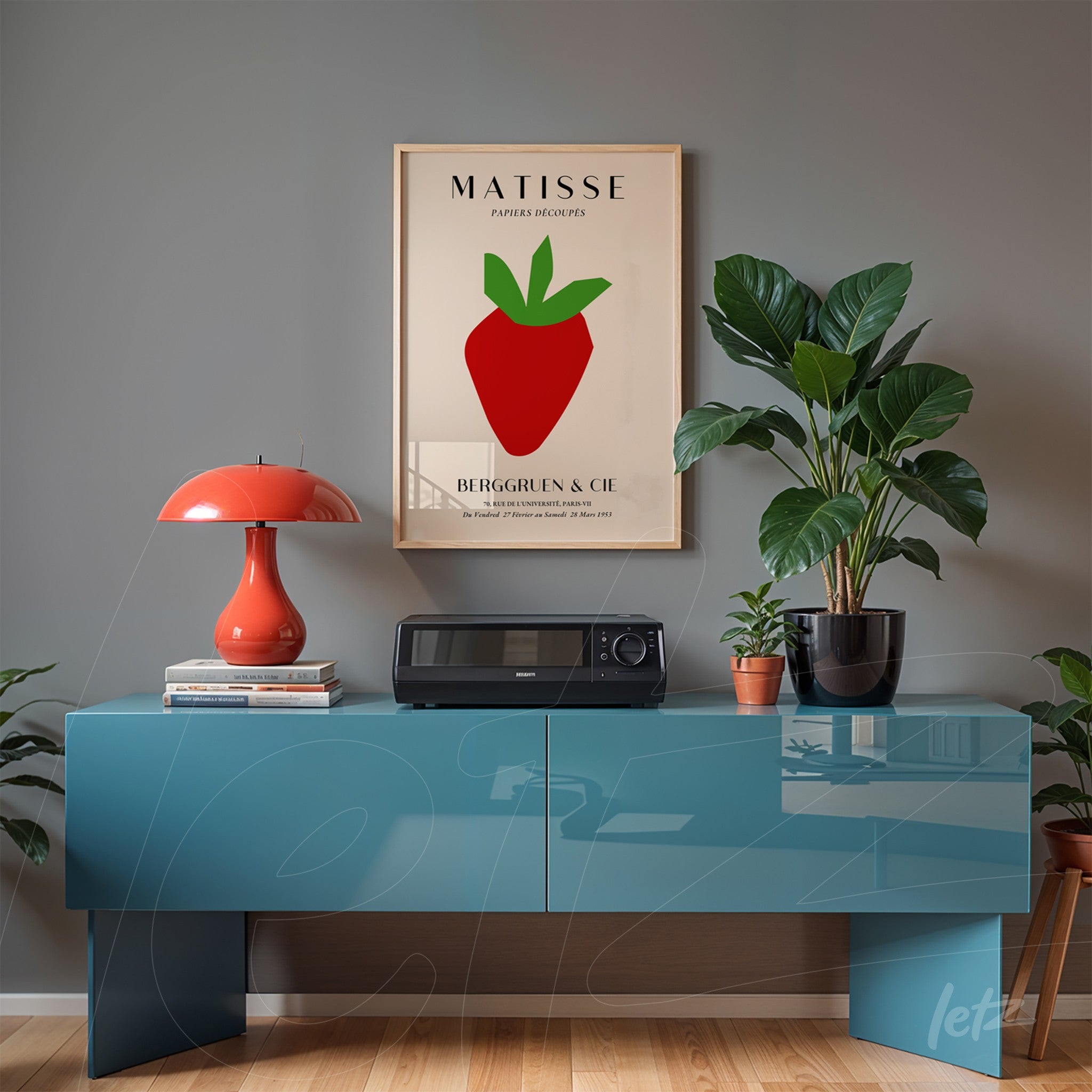 framed modern art of an apple displayed on a blue sideboard with a potted plant beside it
