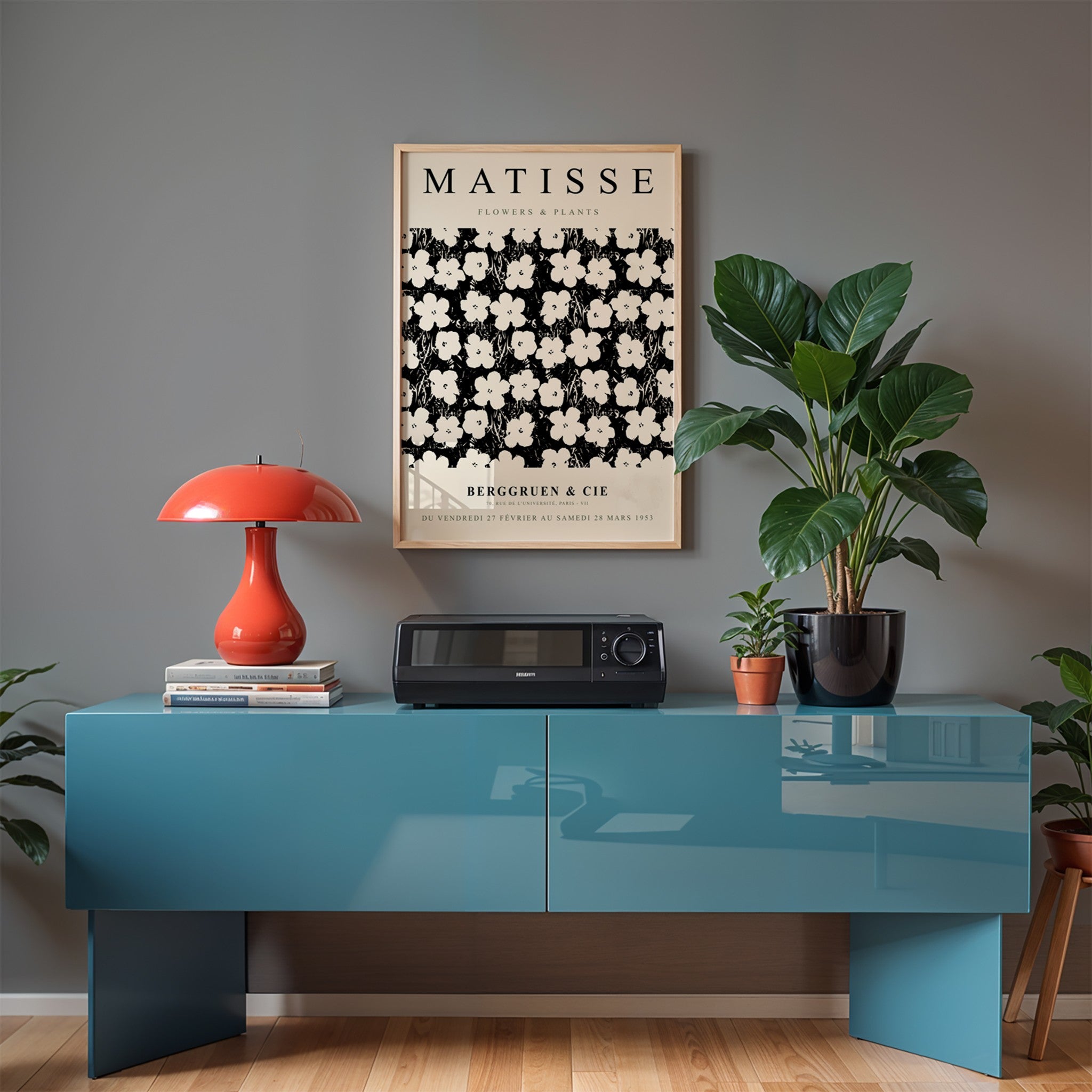 framed wall art featuring floral illustration in light frame displayed above a blue console with a red lamp beside it