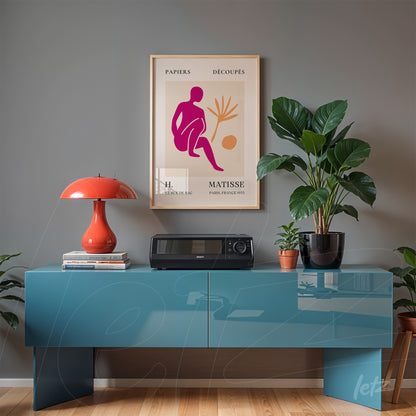 framed wall art featuring modern Matisse artwork on gray wall, displayed over blue furniture with decorative plants and a red lamp