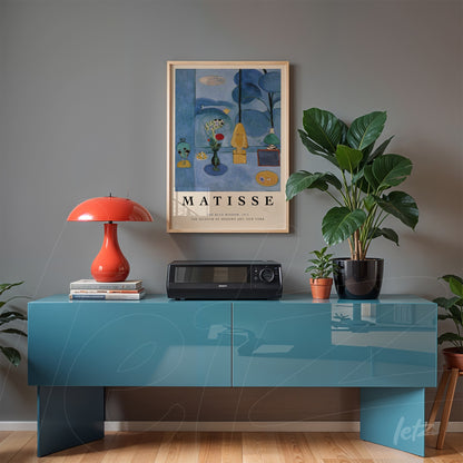 framed wall art by Henri Matisse displayed on gray wall, complementing a blue cabinet with a red lamp