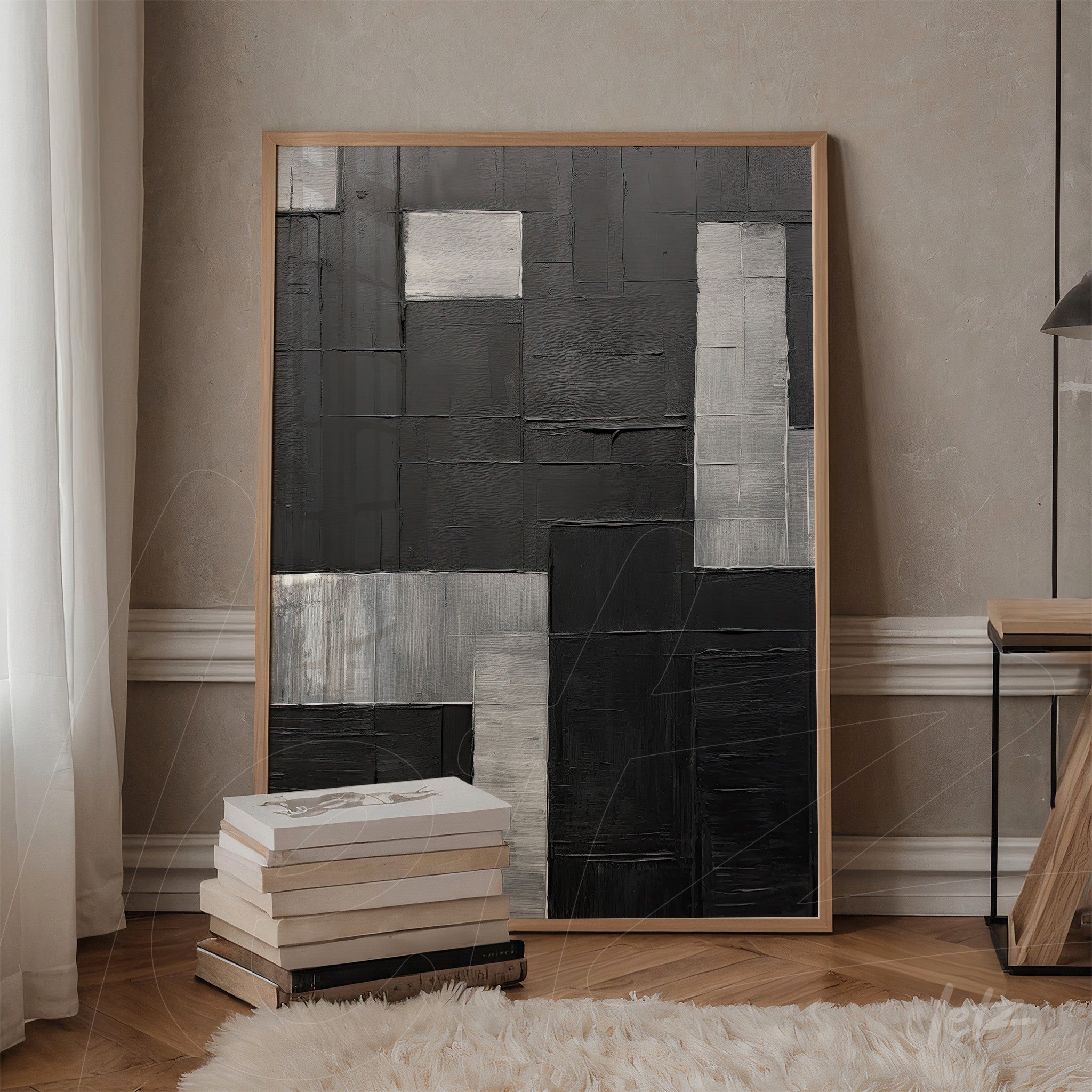 contemporary artwork featuring black, gray, and silver textures in a light wood frame displayed against a beige wall