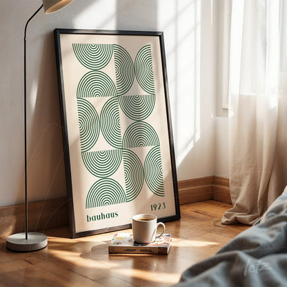 poster print of bauhaus design featuring green concentric circles in black frame, propped on wooden floor