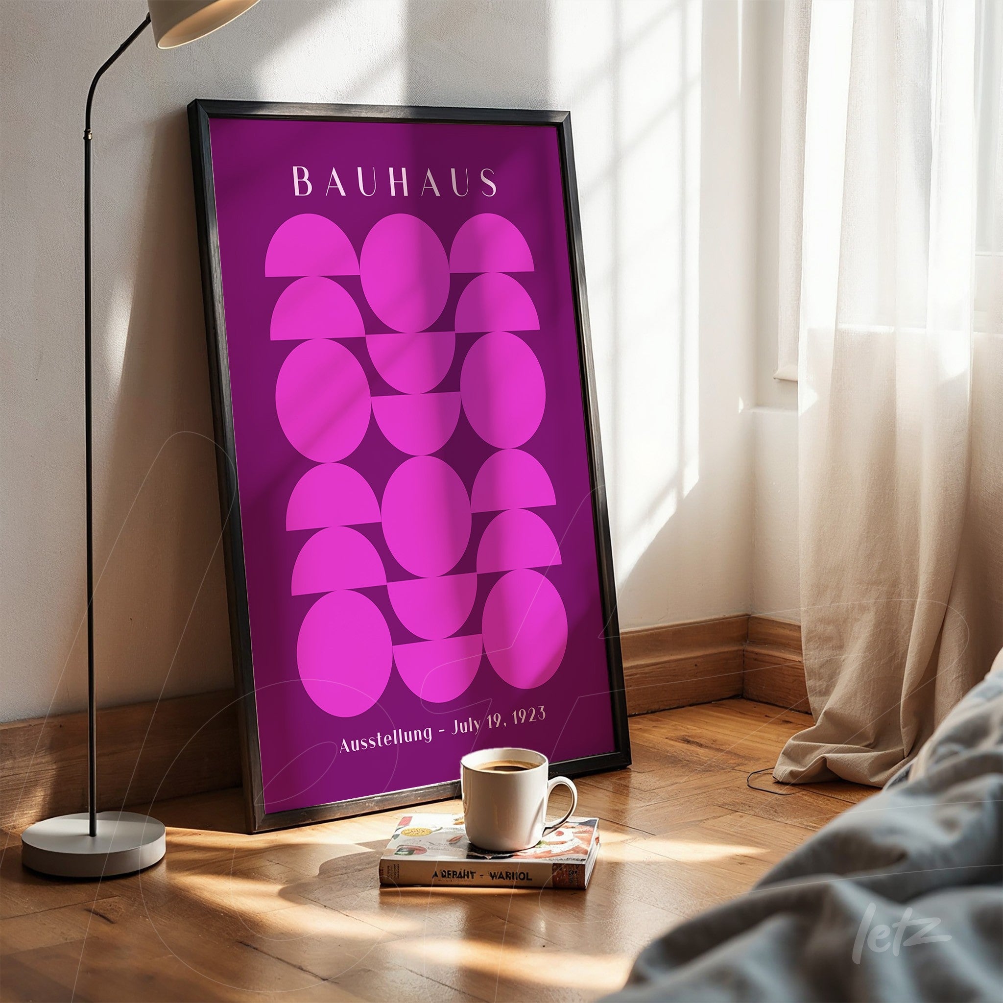 poster print with geometric pink design in a black frame leaning on a wooden floor near a window