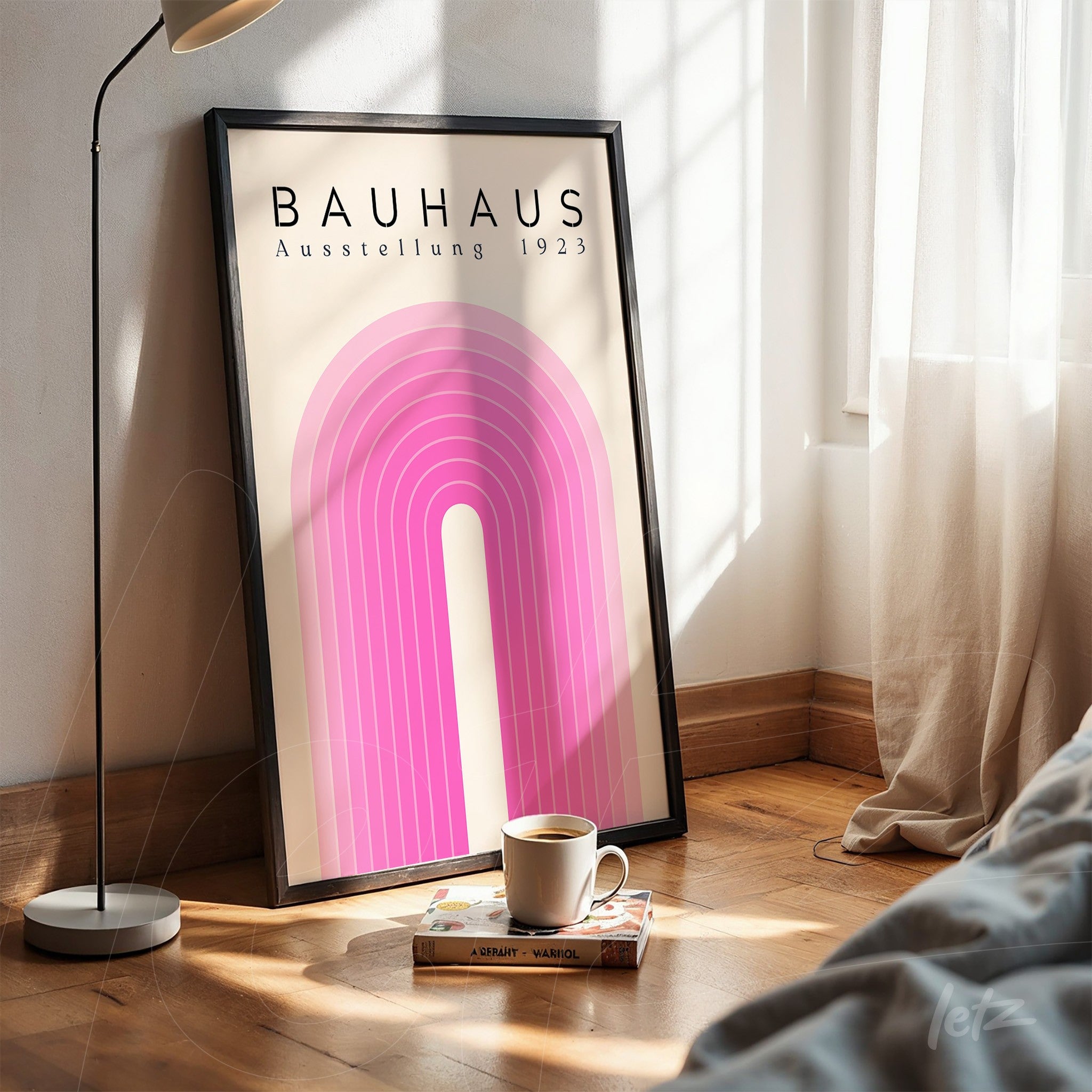 poster print with Bauhaus style geometric design displayed in black frame on wooden floor next to a cup of coffee