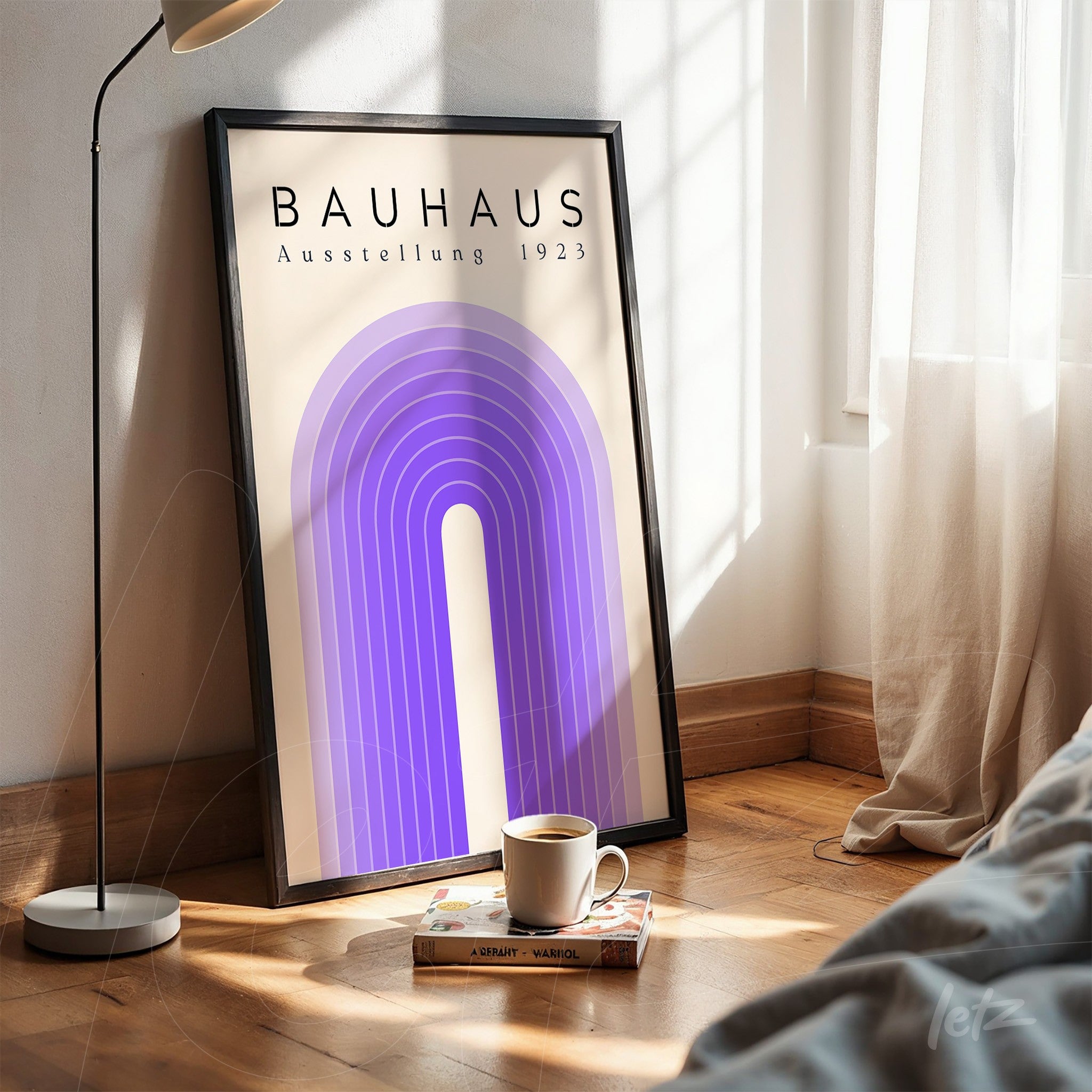 poster print featuring bauhaus art with blue arch and text on beige background, tilted against white wall next to coffee cup