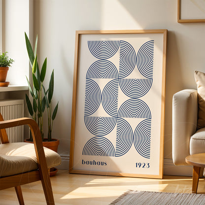 geometric minimalist bauhaus 1923 poster in light wood frame leaning against the floor near plants