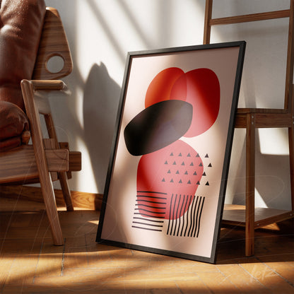 framed abstract art with geometric shapes in red and black tones leaning on wooden floor