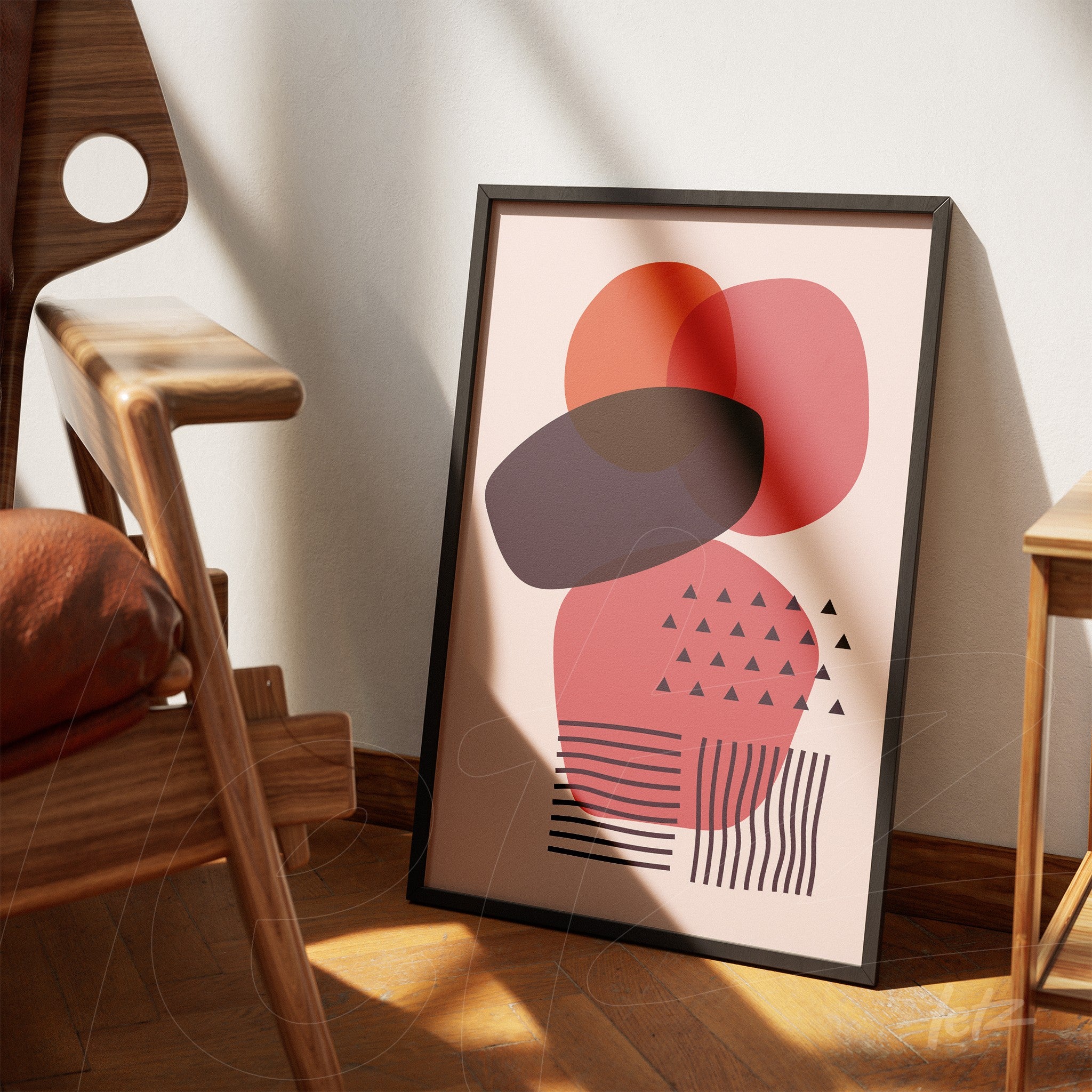 colorful abstract poster with geometric shapes in black frame leaning against a light wall