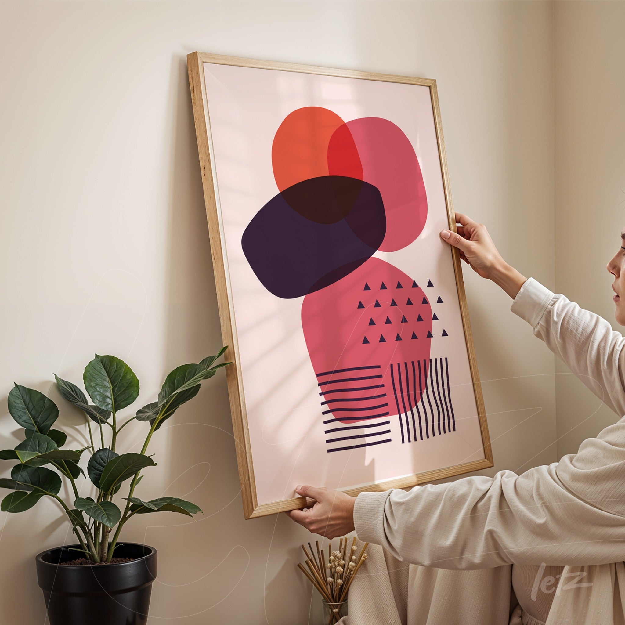 abstract geometric art print in pink and black tones displayed in a light wood frame