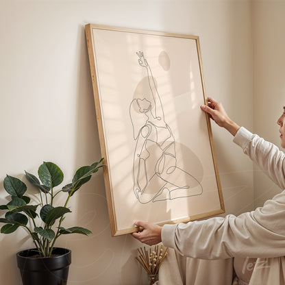 minimalist line art of a seated female figure in black outline framed with light wood, being placed on a beige wall beside a green plant in a black pot