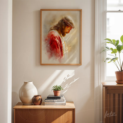 framed wall art depicting the figure of Jesus with a crown of thorns in light wood frame displayed on a wooden table next to decorative vases and plants