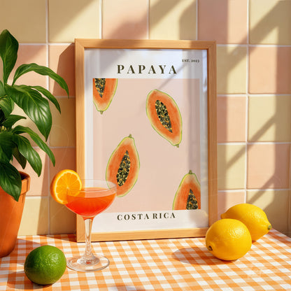 framed art with illustrations of papaya on light background displayed in a kitchen setting with citrus fruits nearby