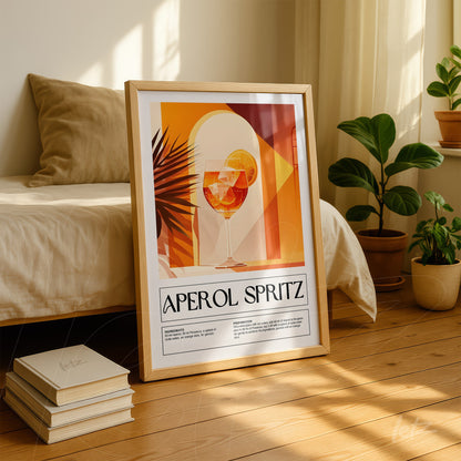 framed artwork of an aperol spritz cocktail in warm geometric tones displayed against a bed and next to indoor plants