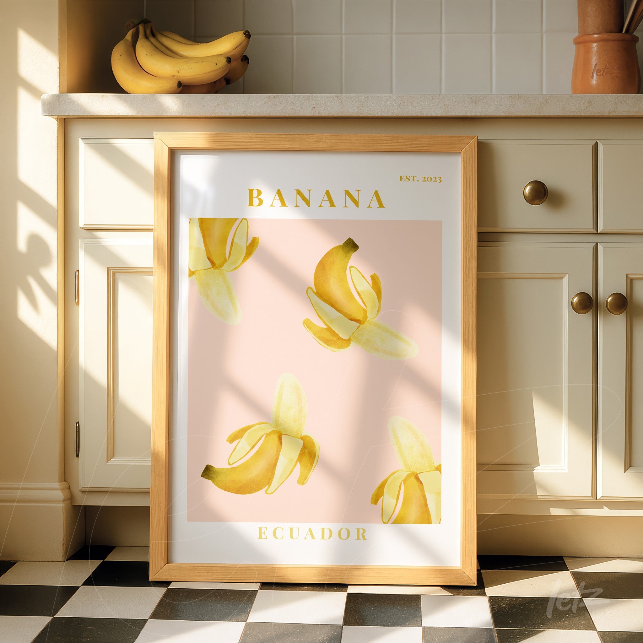 framed artwork featuring yellow bananas on a light pink background with a light wood frame