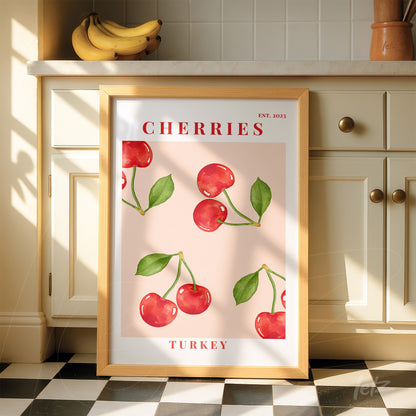 framed art featuring red cherries on a pink background with light wood frame displayed in a kitchen setting with natural light