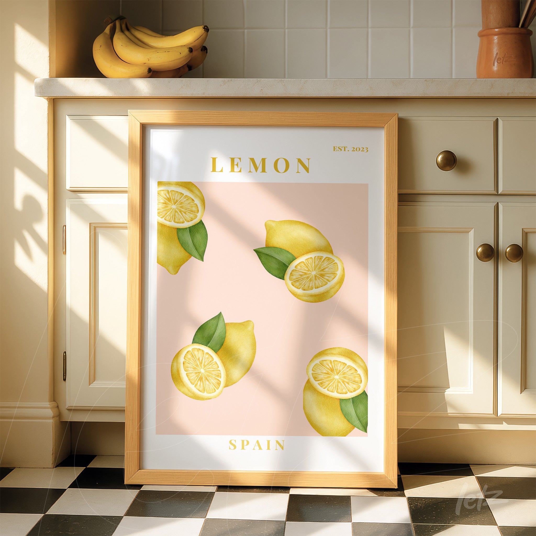 framed wall art featuring illustrations of lemons on a pink background with light wood frame