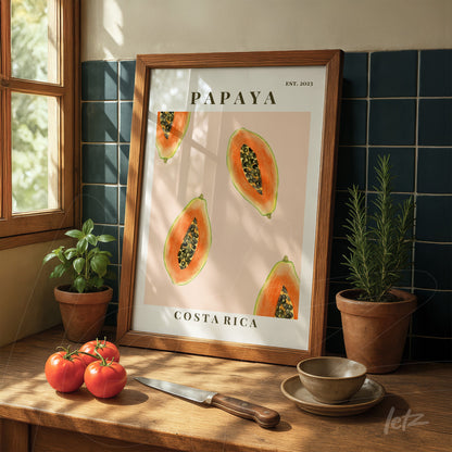 framed wall art featuring papaya illustration on pink background displayed on wooden table with herbs and tomatoes
