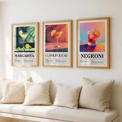 series of three framed prints of iconic cocktails in gold frames against a light background with neutral cushions