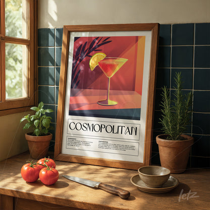 framed artwork of cosmopolitan cocktail on light wood table with tomatoes and herbs nearby