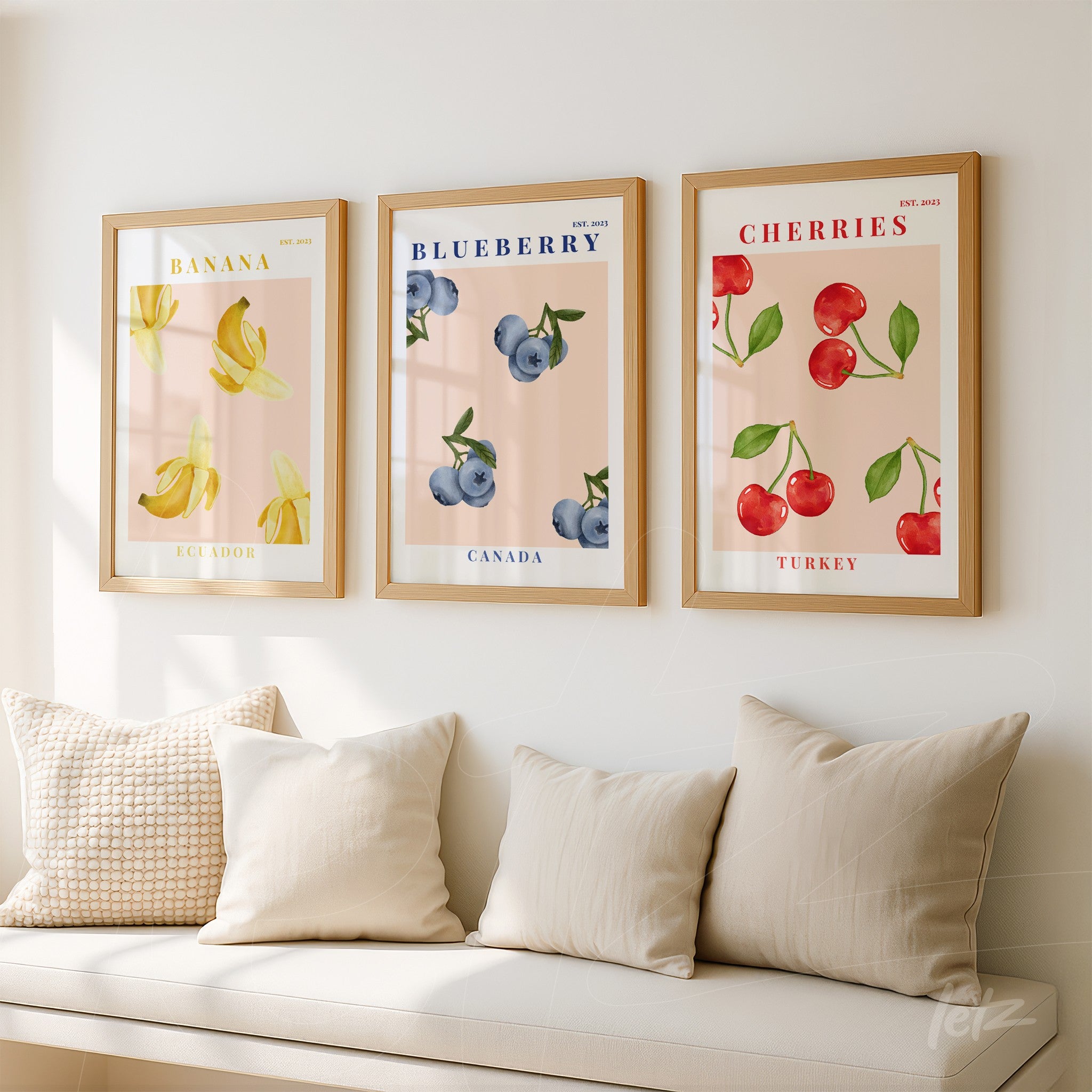 composition of framed wall art featuring fruit illustrations in light wood frame, including banana, blueberry, and cherries on light pink background