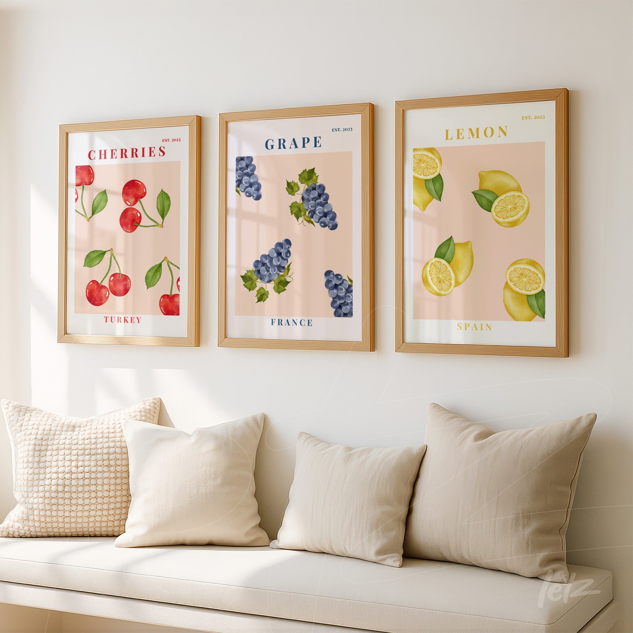 set of framed artworks featuring stylized fruits on pink backgrounds, including cherries, green grapes, and yellow lemons, displayed on a white wall