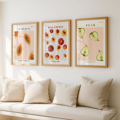 collection of framed wall art featuring illustrations of papaya, peach, and pear in light wood frames on white wall