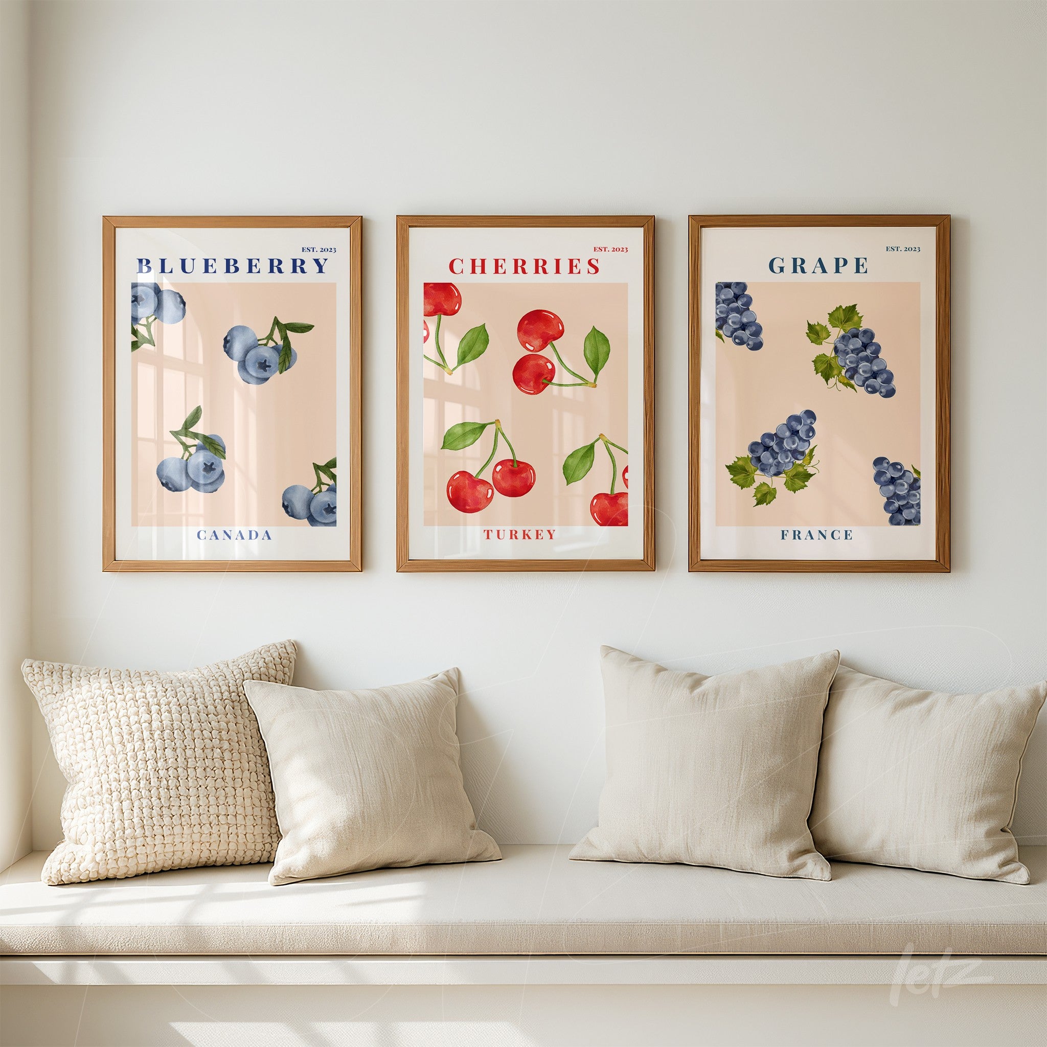 composition of framed wall art featuring blueberries, cherries, and grapes with light wood frames against a soft pink background