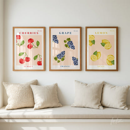 collection of three framed artworks featuring illustrated fruits with cherry red, purple grapes, and yellow lemons against a soft neutral background
