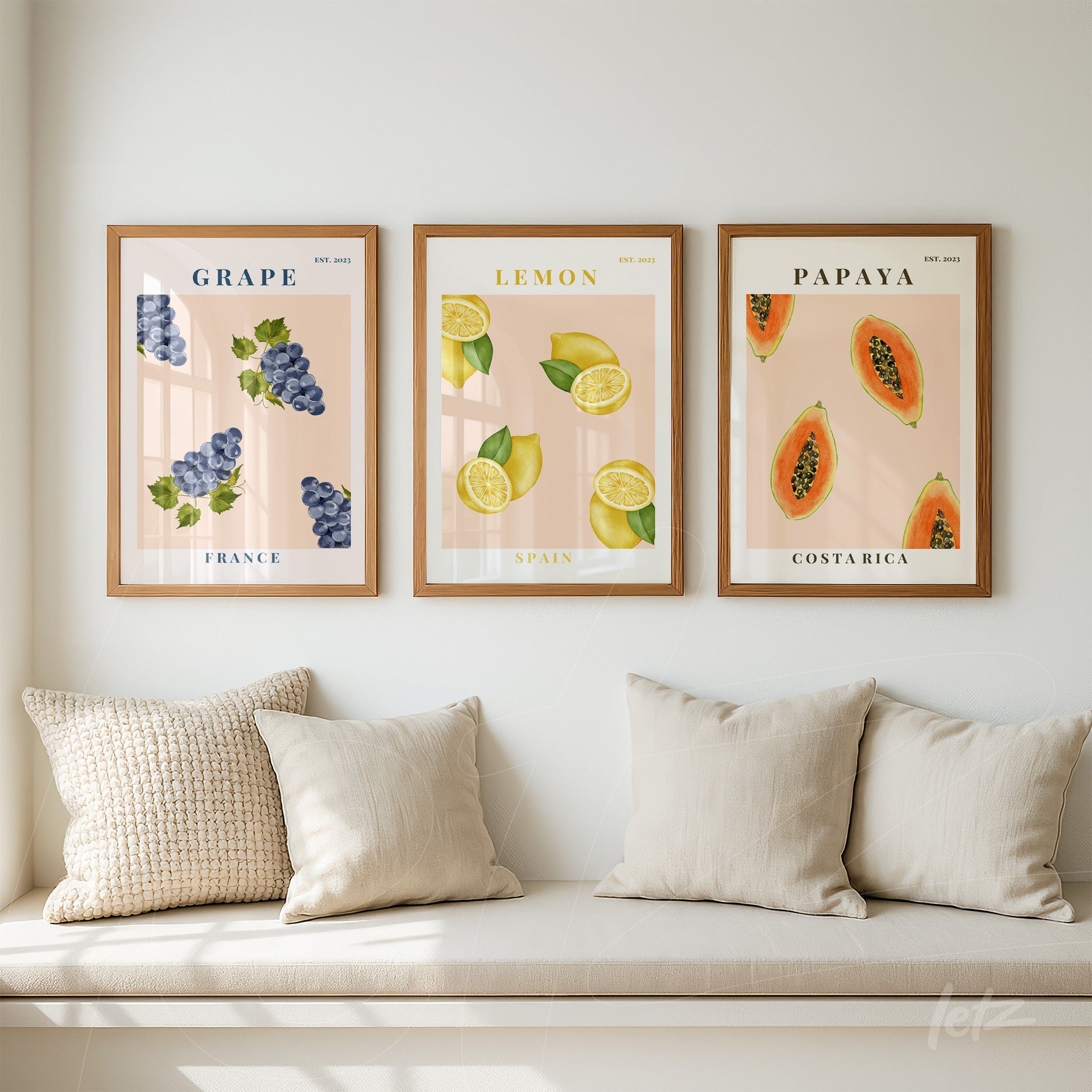 set of three framed wall art pieces featuring fruit illustrations: grapes on pink background with wooden frame, sliced lemons on soft background with gold frame, and papayas on light backdrop with wooden frame