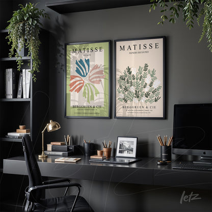 composition of two framed wall arts in black frames, one featuring colorful leaves and the other with green flowers, displayed above a dark desk