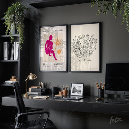 composition of framed contemporary art featuring a stylized pink figure and a foliage illustration on light background, set against a dark gray wall in a modern office environment