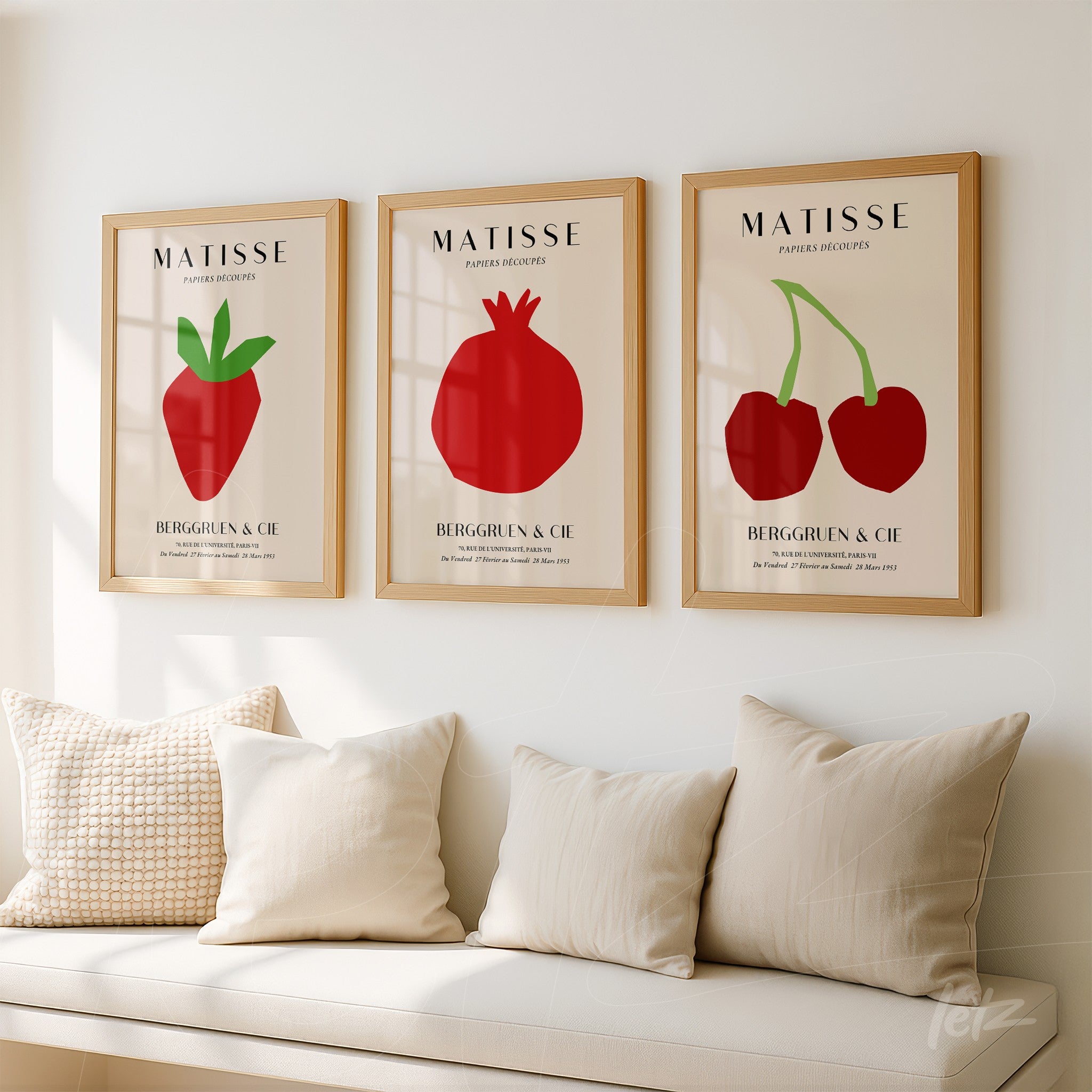 series of decorative wall art featuring red fruit illustrations in light wood frames on neutral wall