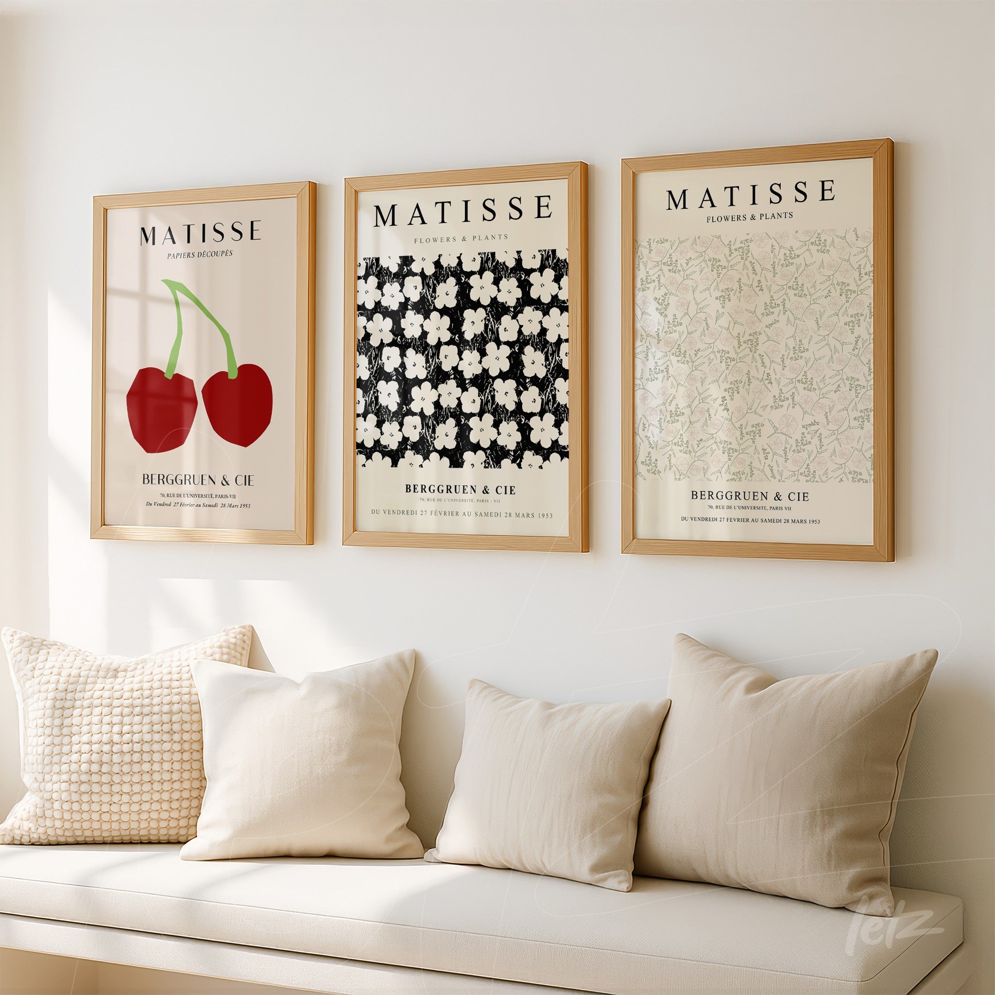 composition of three framed artworks with illustrations of flowers and fruits above a white wall, displayed over a sofa with cushions