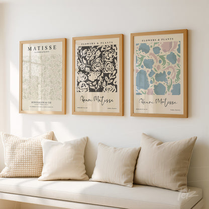 set of wall art prints featuring floral patterns in light wooden frames above a sofa with neutral cushions