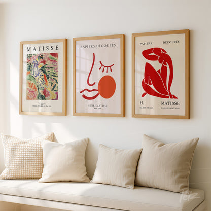 composition of three framed wall art pieces by Henri Matisse in light wood frames on a white wall