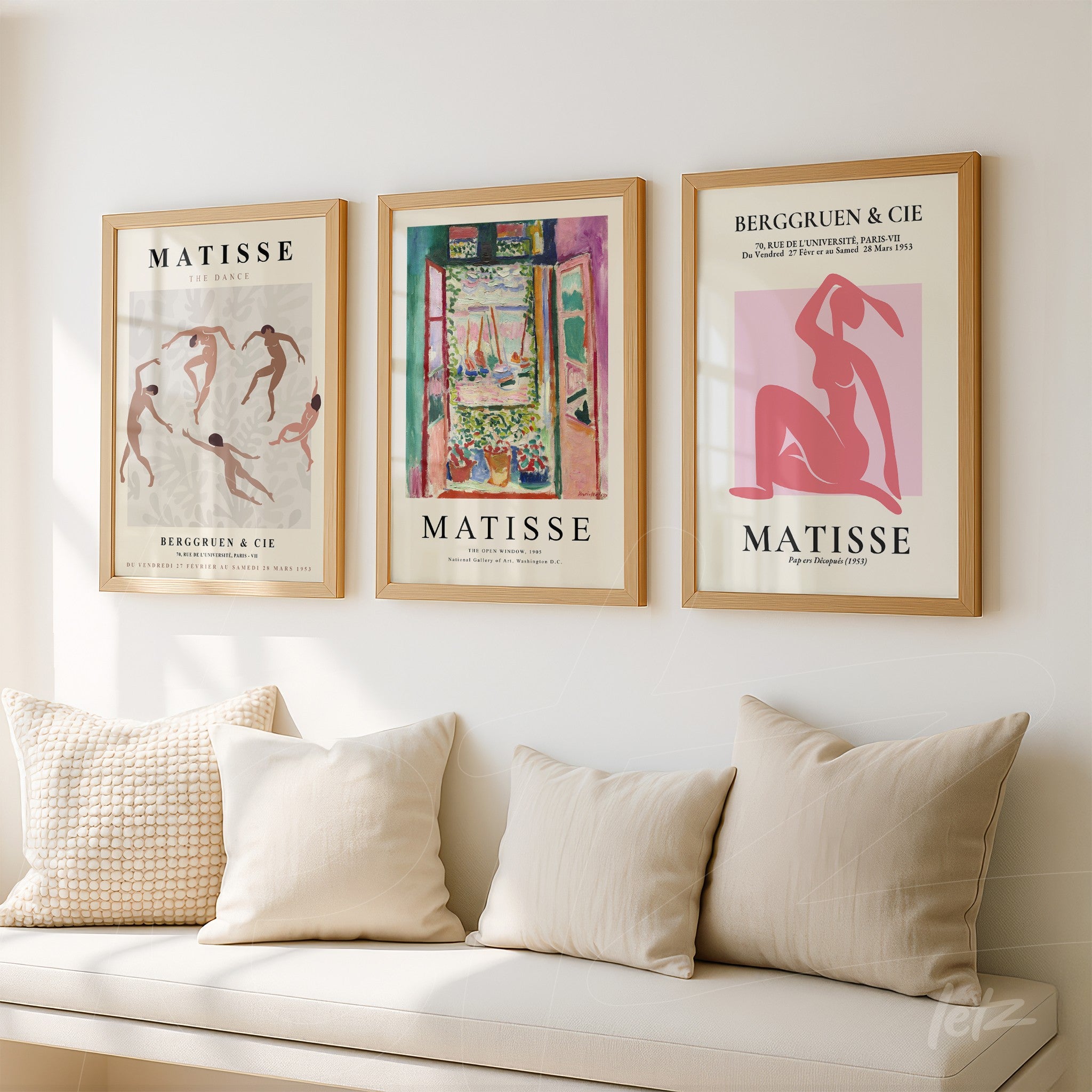set of three decorative wall art pieces featuring henri matisse's work in light wood frames displayed on a white wall with beige cushions on a sofa in the background