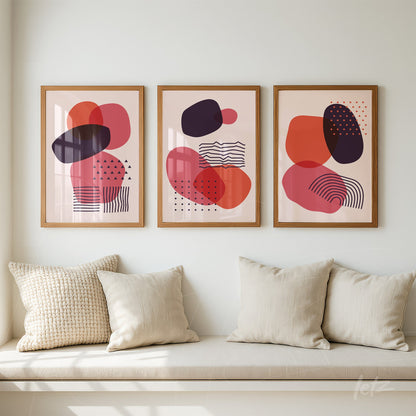 series of three poster prints featuring abstract shapes in red and black tones, each framed in light wood and displayed on a white wall
