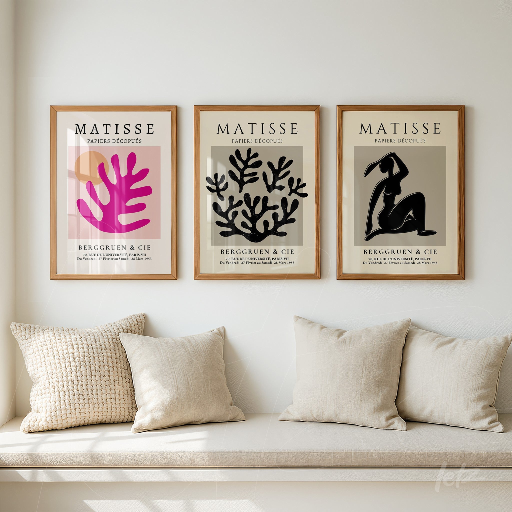 composition of three cut-out style wall art pieces by Matisse in light wood frames above a neutral sofa