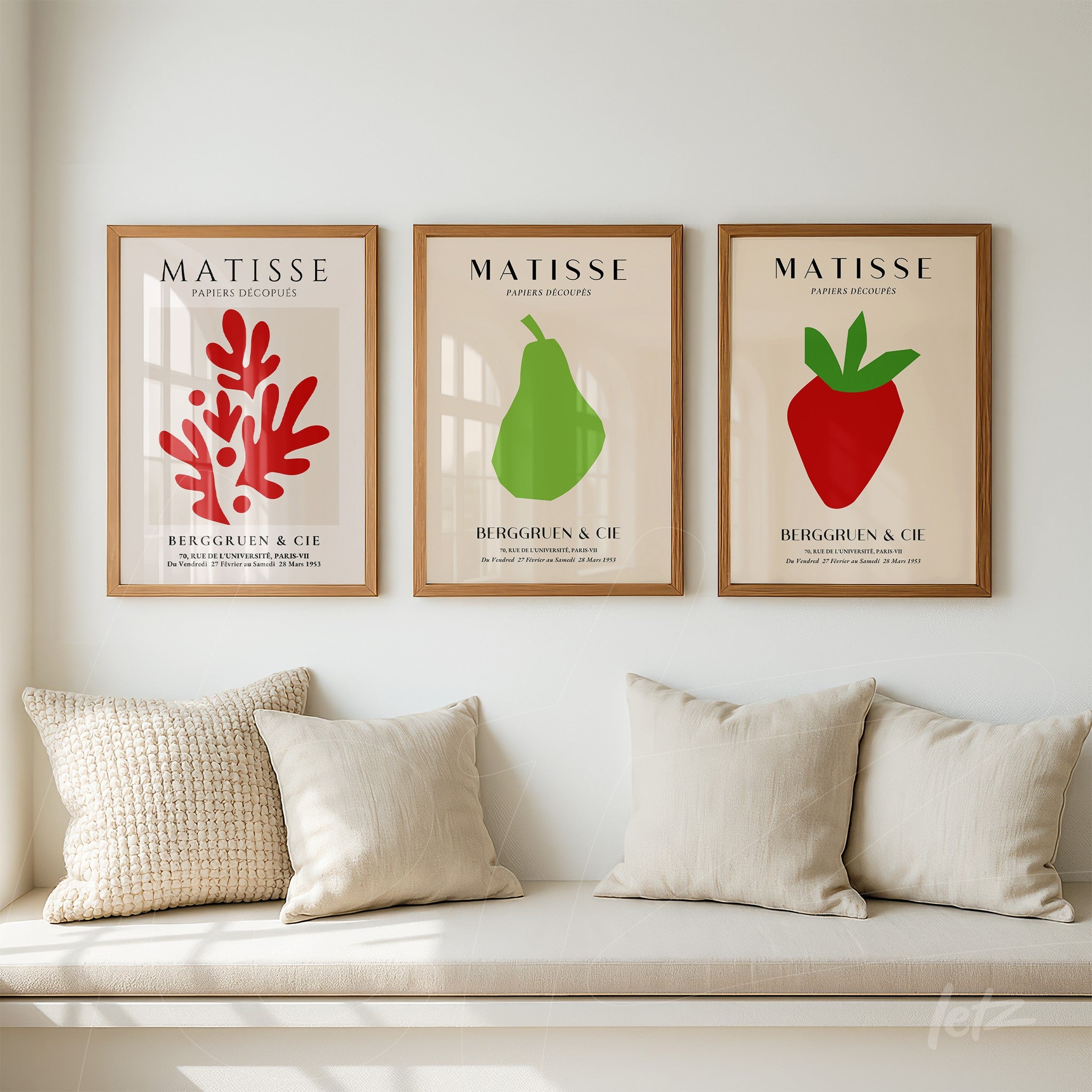 composition of three framed wall art pieces featuring simple illustrations of fruits and vegetation in light wood frames displayed above a neutral sofa