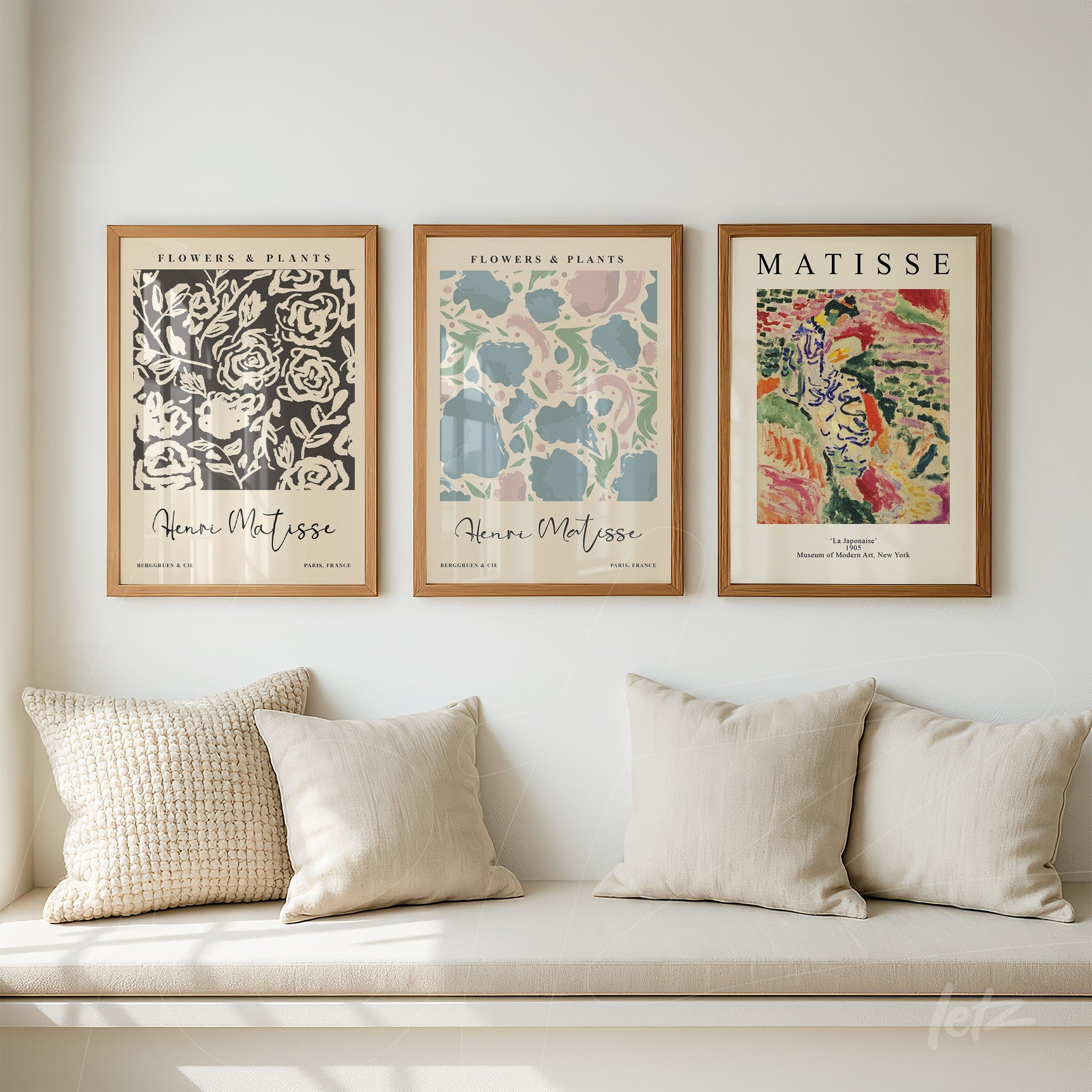 collection of three modern art framed prints in light wood frames displayed above a sofa with light cushions