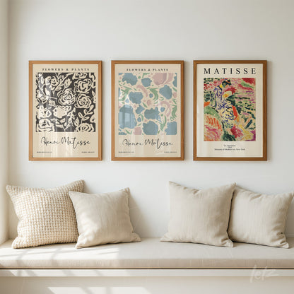 collection of three modern art framed prints in light wood frames displayed above a sofa with light cushions